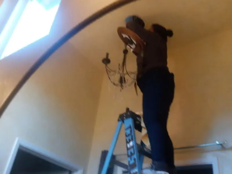 Electrician installing a chandelier in a Griswold residence